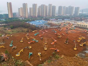 caption: Excavators are seen at the construction site of a medical center being built in Wuhan, China, to treat patients of the coronavirus outbreak. Ground was broken on Jan. 24. The scheduled opening is Feb. 3.