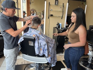 caption: Jennifer Nuno checks her 11-year-old son's back-to-school haircut in the Lincoln Village neighborhood of Milwaukee on August 21.