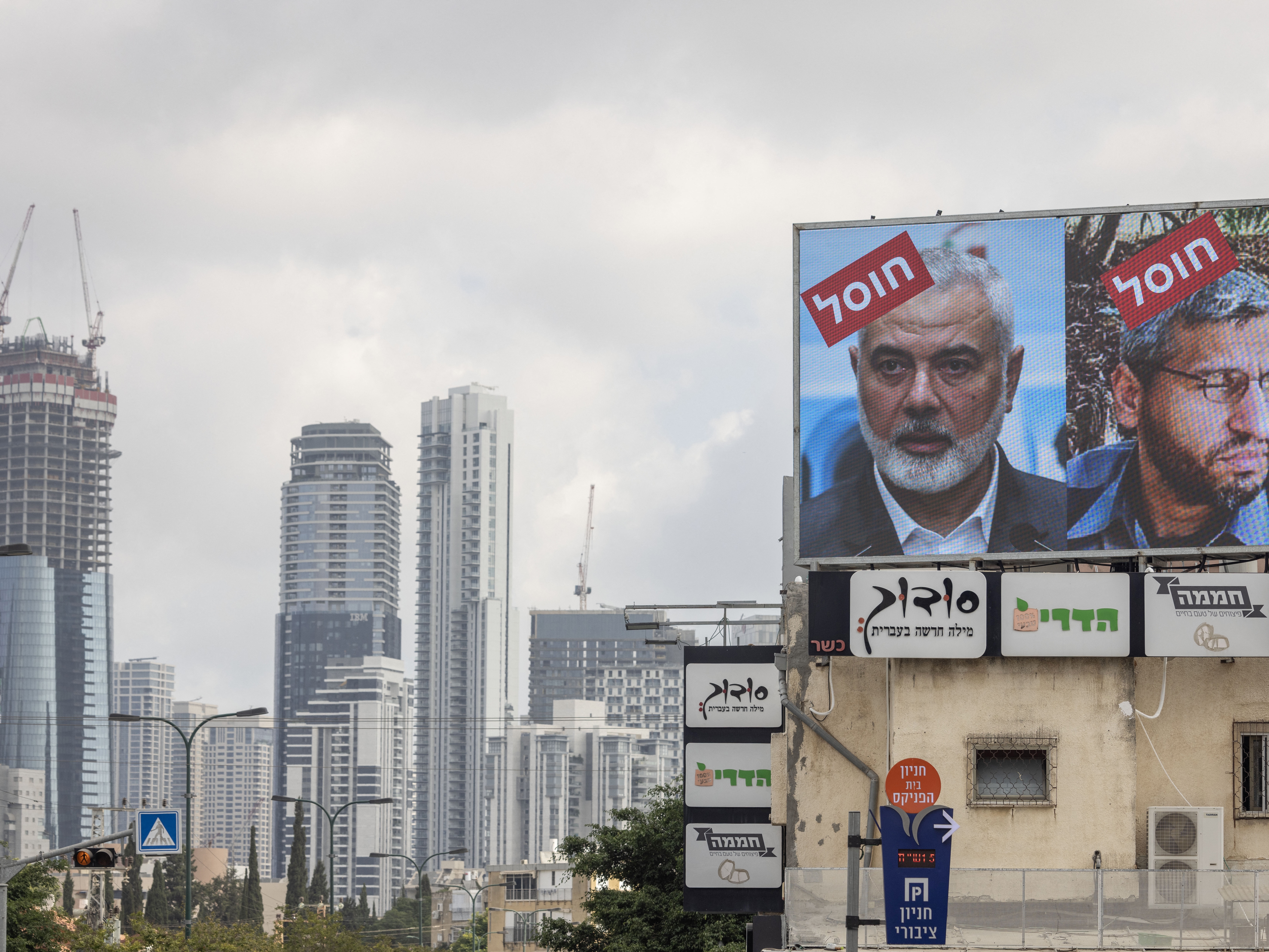 caption: A billboard displays portraits of Hamas leaders Mohammed Deif and Ismail Haniyeh with the word "assassinated" in Hebrew, in Tel Aviv, Aug. 2, 2024.