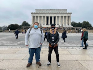 caption: Distant cousins Cody (left) and Andrew meet in Washington, D.C. Cody is a member of a Three Percenter-affiliated militia group, and Andrew is an organizer with Black Lives Matter activists. The two connected on Facebook and have gotten to know each other while researching their ancestry.