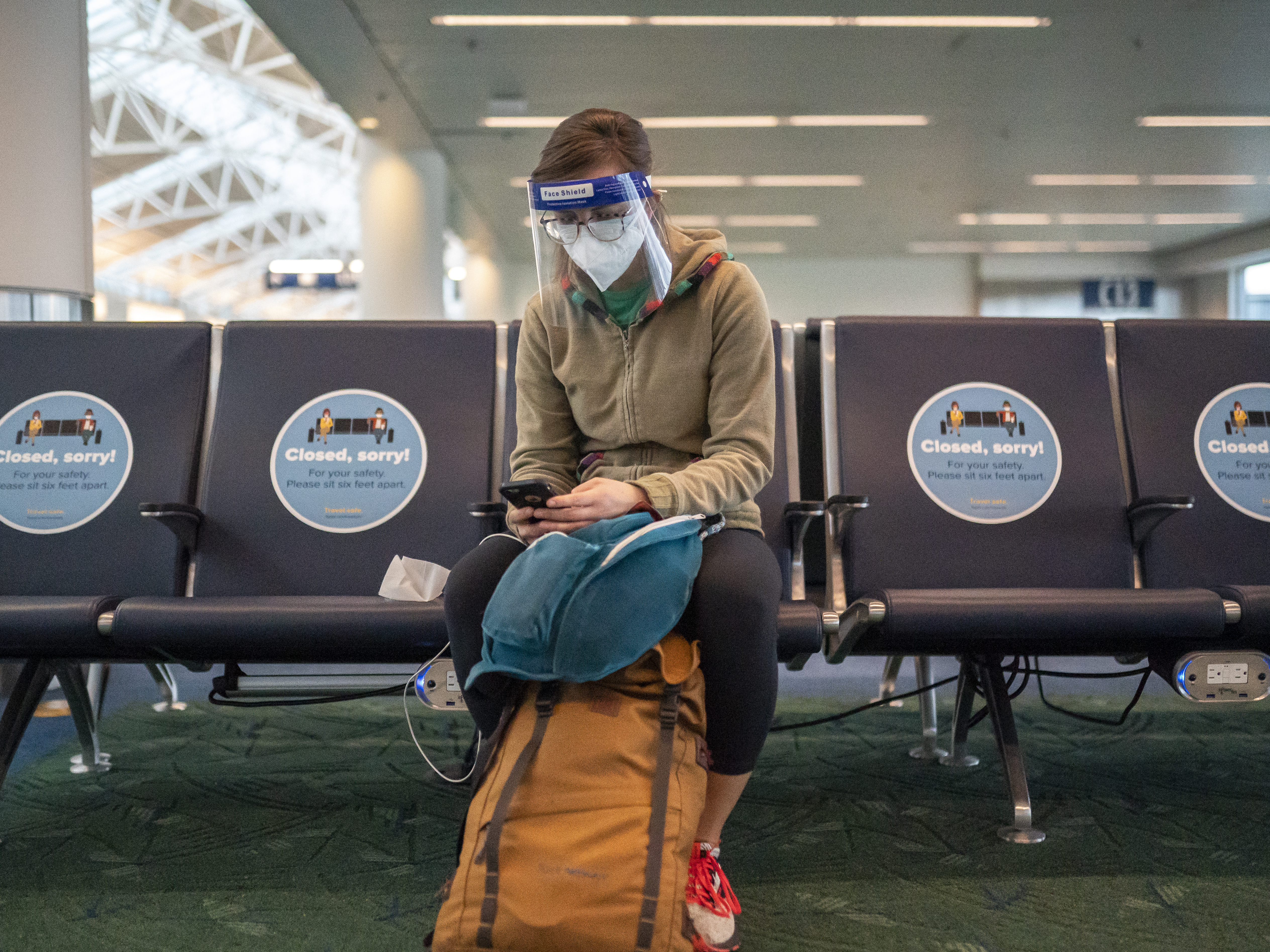 caption: A traveler waits for a flight at Portland International Airport in Oregon last week. Public health experts say it's important that people who traveled or gathered with others are especially careful over the next two weeks.