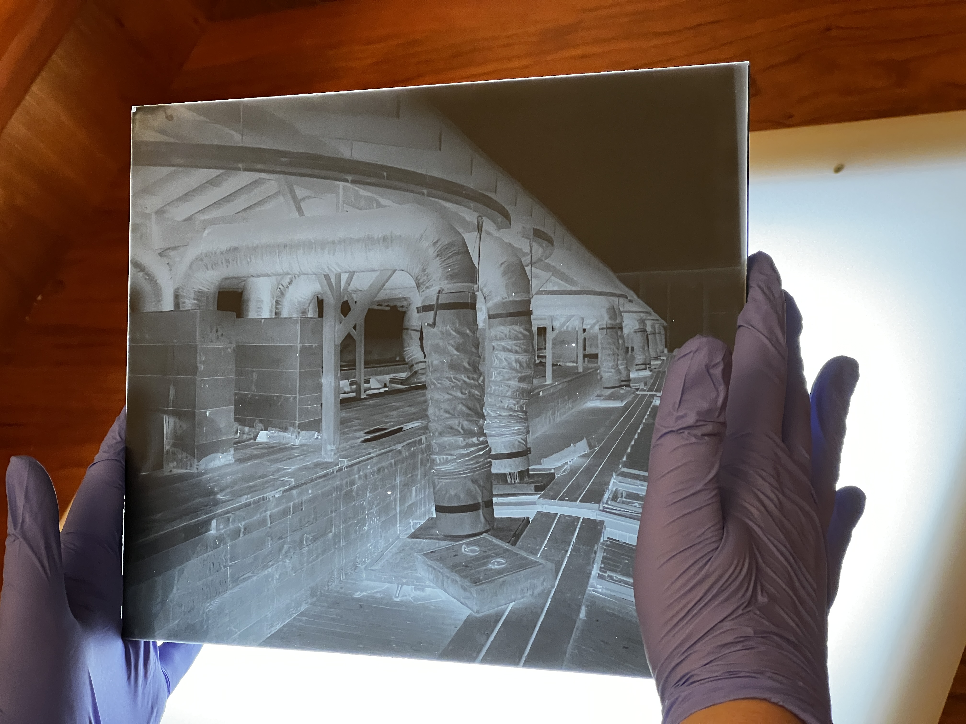 caption: A glass-plate negative from photographer Asahel Curtis shows tubes hooked to a train car in Zillah, Washington. The hand-written note card from Curtis himself says this station was for loading fruit into a "pre-cooking" car. 
