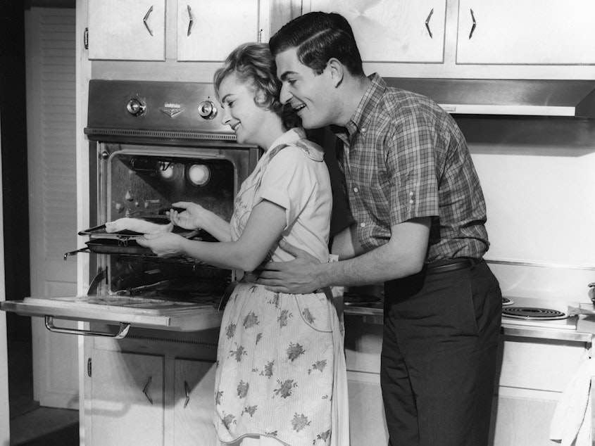 caption: UNITED STATES - CIRCA 1950s: Couple in kitchen. Women in opposite-sex marriages may be contributing more to their families' income, but they're also still shouldering more of the workload at home, according to a new report.