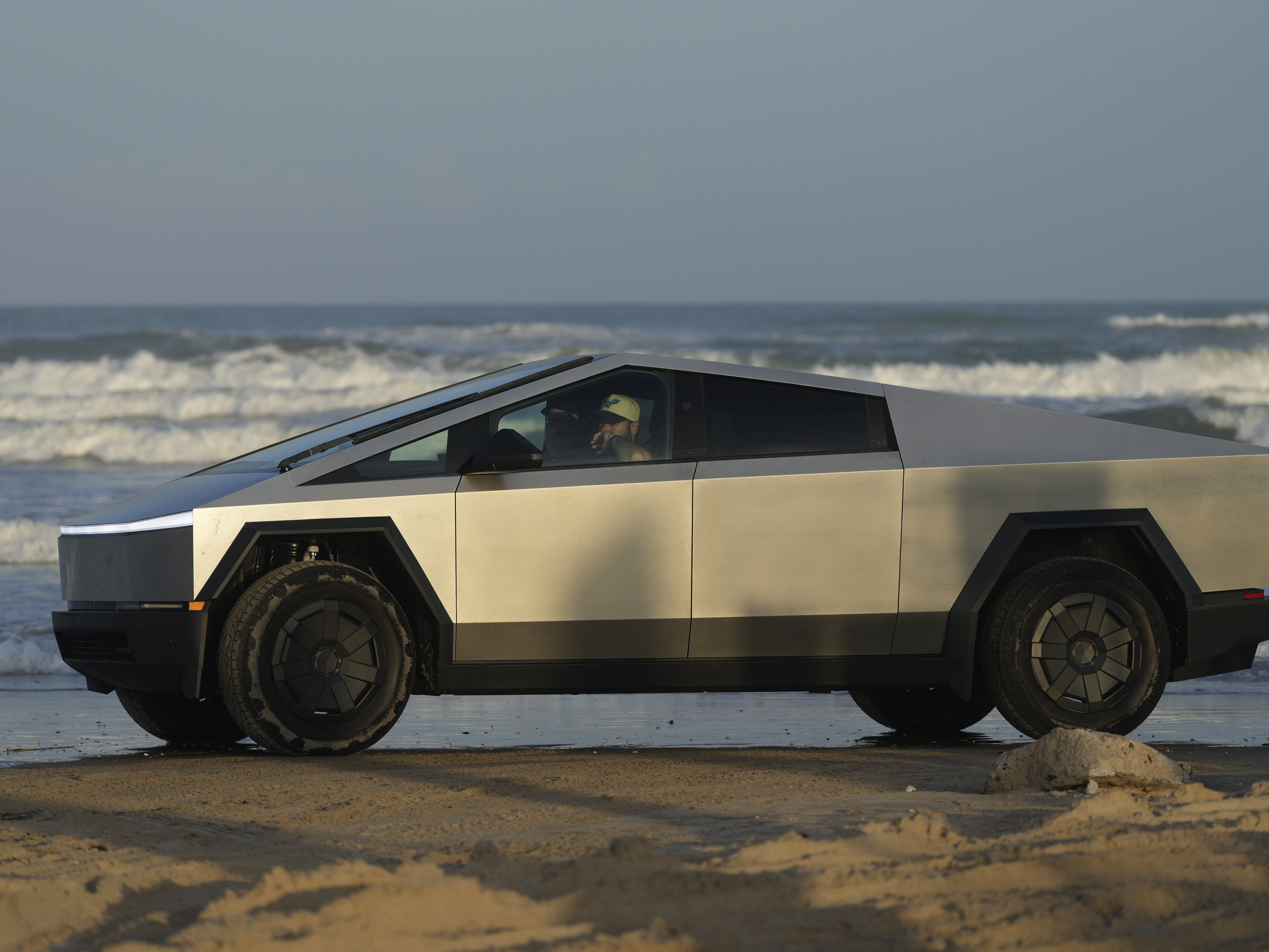caption: A Tesla Cybertruck moves along the beach in Boca Chica, Texas, on Nov. 18, 2024.