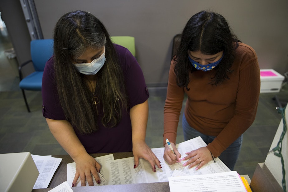 caption: Director of Island Drug, Fran Castro, left, and customer service representative Virginia Martinez, right, place the date as well as labels indicating the type of vaccination, lot number and expiration date on CDC vaccination record cards on Wednesday, April 7, 2021, at Island Drug in Oak Harbor.