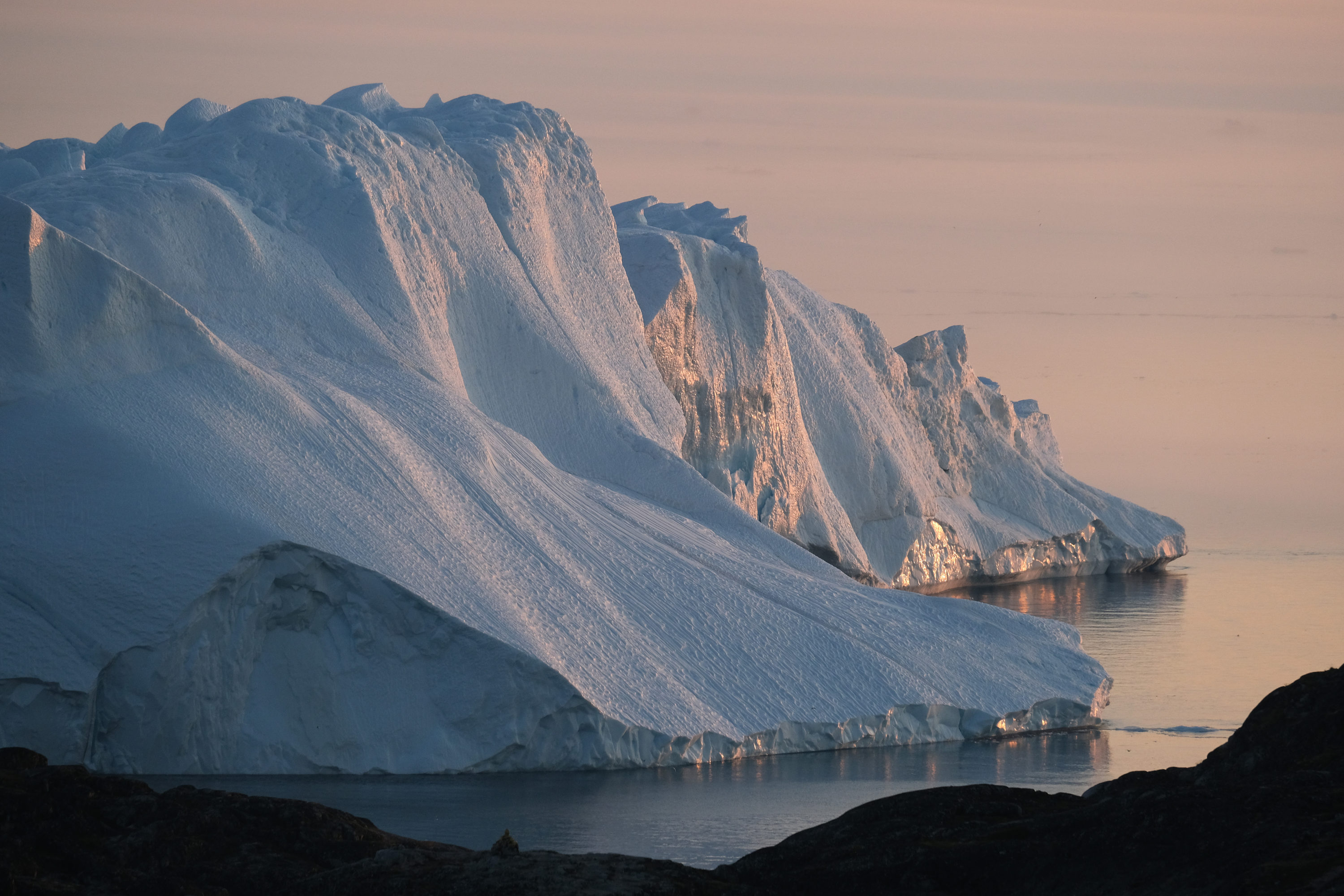 caption: A massive iceberg stands at the mouth of the Ilulissat Icefjord during a week of unseasonably warm weather on Aug. 4, 2019 near Ilulissat, Greenland. (Sean Gallup/Getty Images)