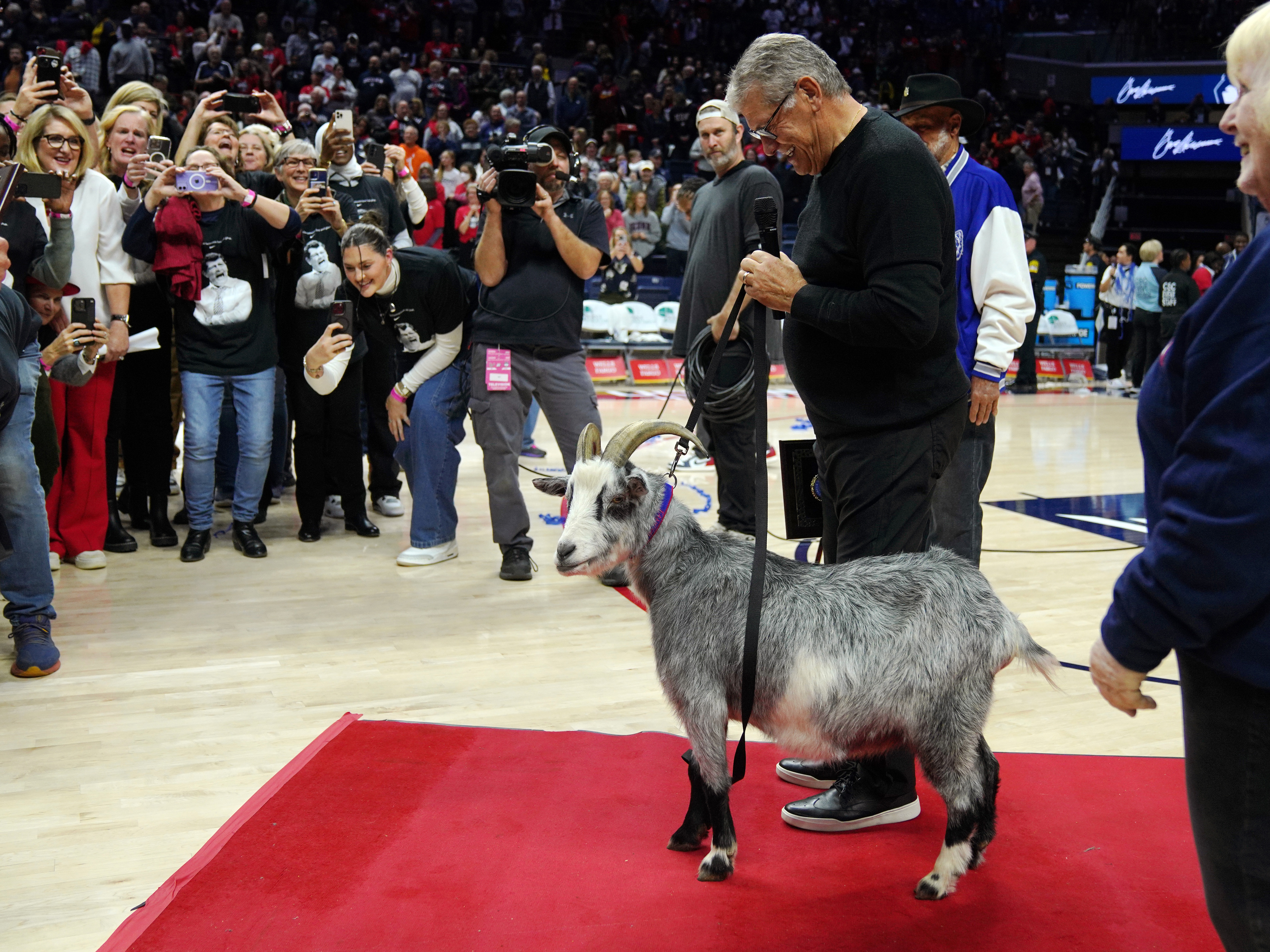 caption: Connecticut Huskies head coach Geno Auriemma is presented with a goat after becoming the NCAA all-time basketball wins leader on Wednesday in Storrs, Conn.