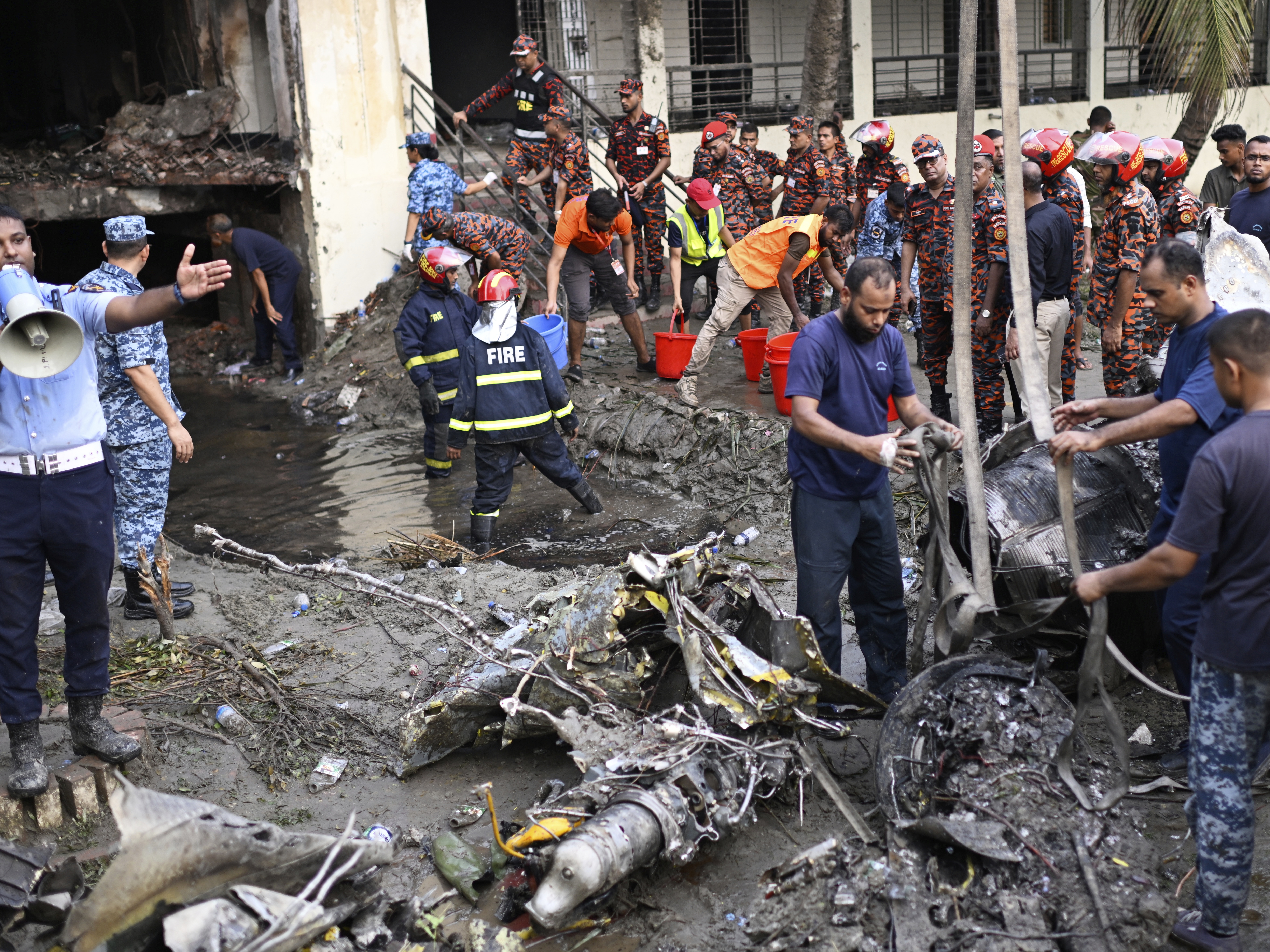 caption: Firefighters work at the site of a Bangladesh Air Force training aircraft that crashed into a school campus shortly after takeoff in Dhaka, Bangladesh, Monday.