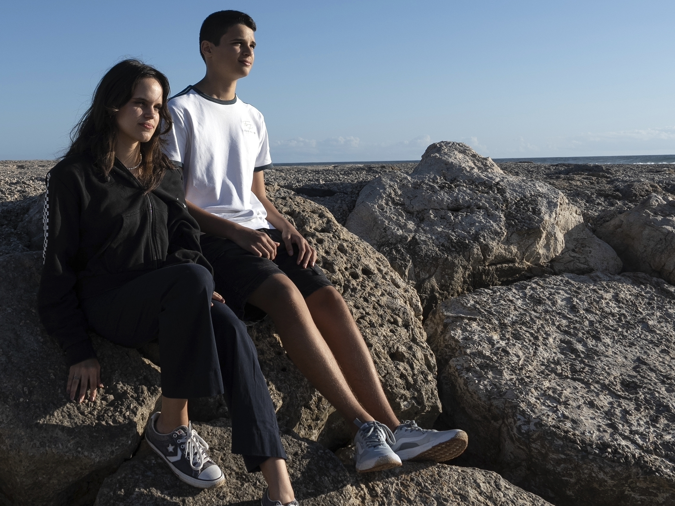 caption: Siblings Sofia Oliveira, 18, and Andre Oliveira, 15, pose for a picture at the beach in Costa da Caparica, south of Lisbon, Wednesday, Sept. 20, 2023.