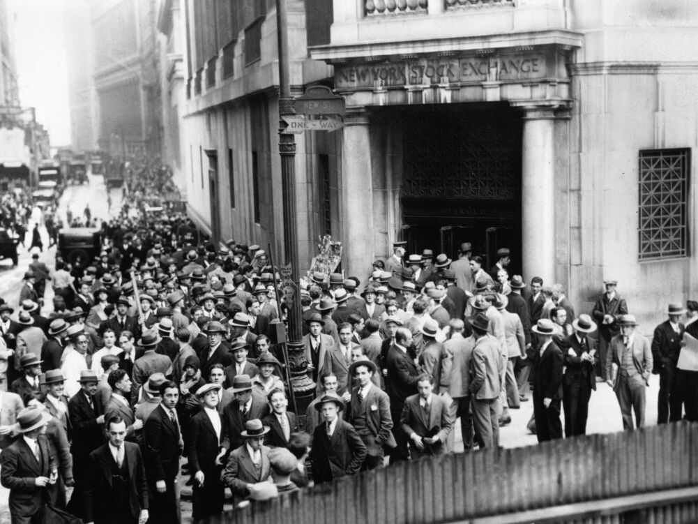 caption: Crowds outside the New York Stock Exchange during the Wall Street Crash in the Financial District of Lower Manhattan, New York City, New York, Oct. 1929.