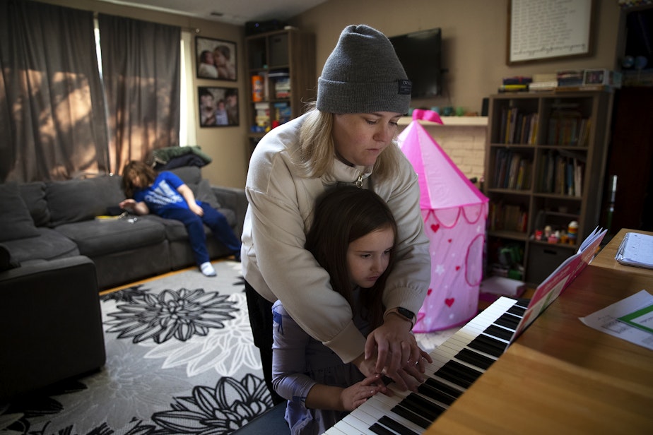 caption: Lara Allen helps her 7-year-old daughter Lily with piano practice after school on Wednesday, Nov. 22, 2023, at their home in Kenmore, Washington. 