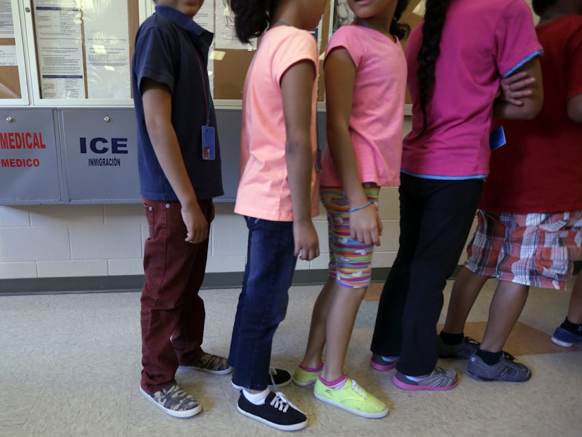 caption: Detained immigrant children line up at a temporary home for immigrant women and children in Karnes City, Texas.