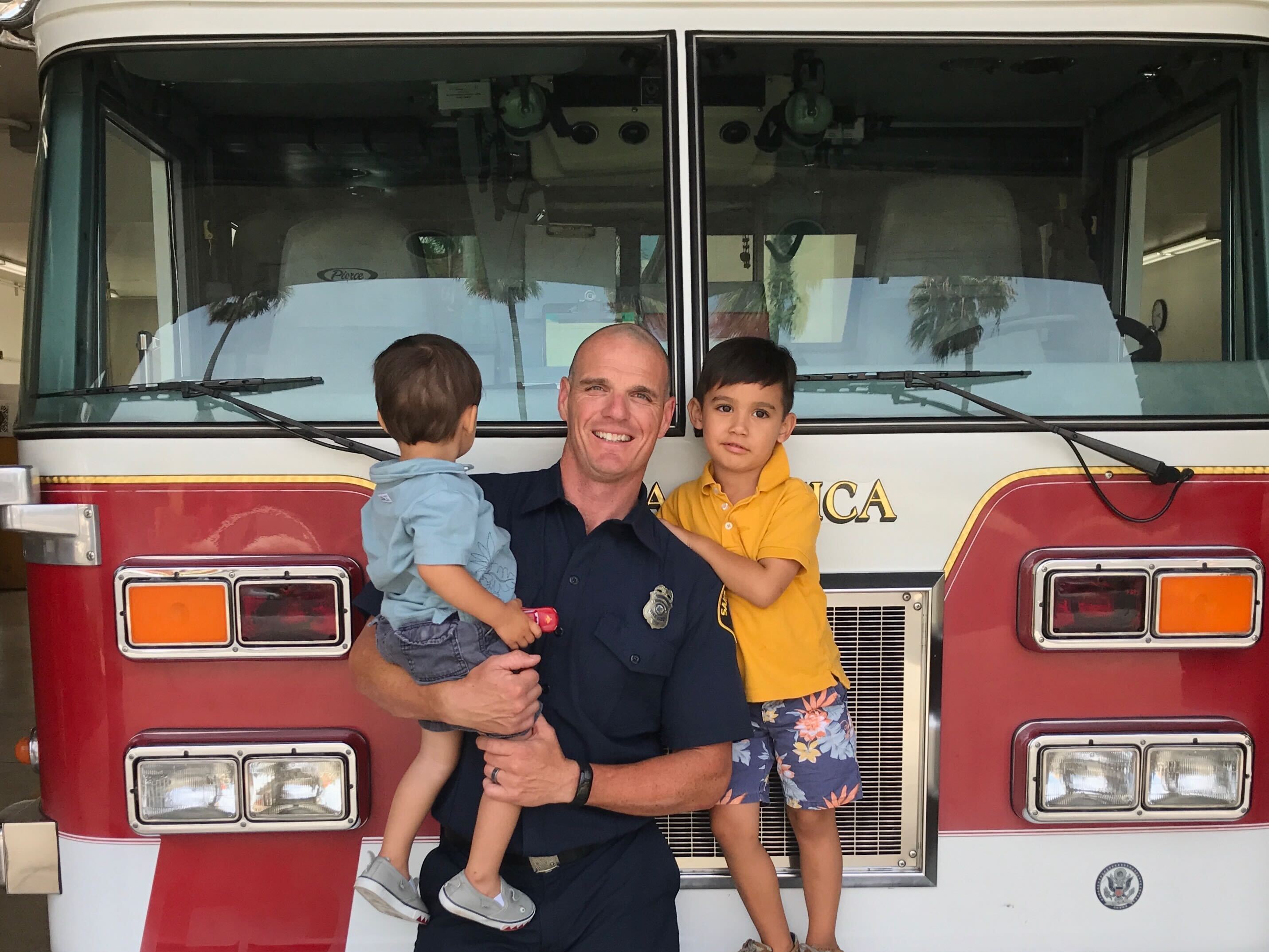 caption: <em>Old photo of fire captain Shane Lawlor and his two sons at a Santa Monica Fire Station. Lawlor has been a firefighter for 17 years. He was dispatched last week to the Pacific Palisades and is still fighting the fires there.</em>