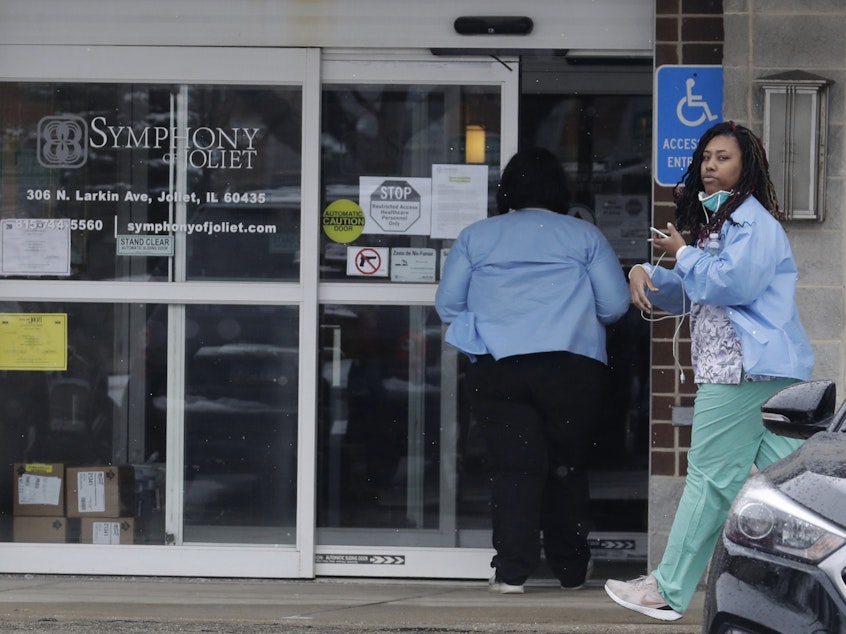 caption: Employees of the Symphony of Joliet nursing home in Joliet, Ill., go to work last Friday. At least 21 people, including two staff members, have died of COVID-19 at the facility.