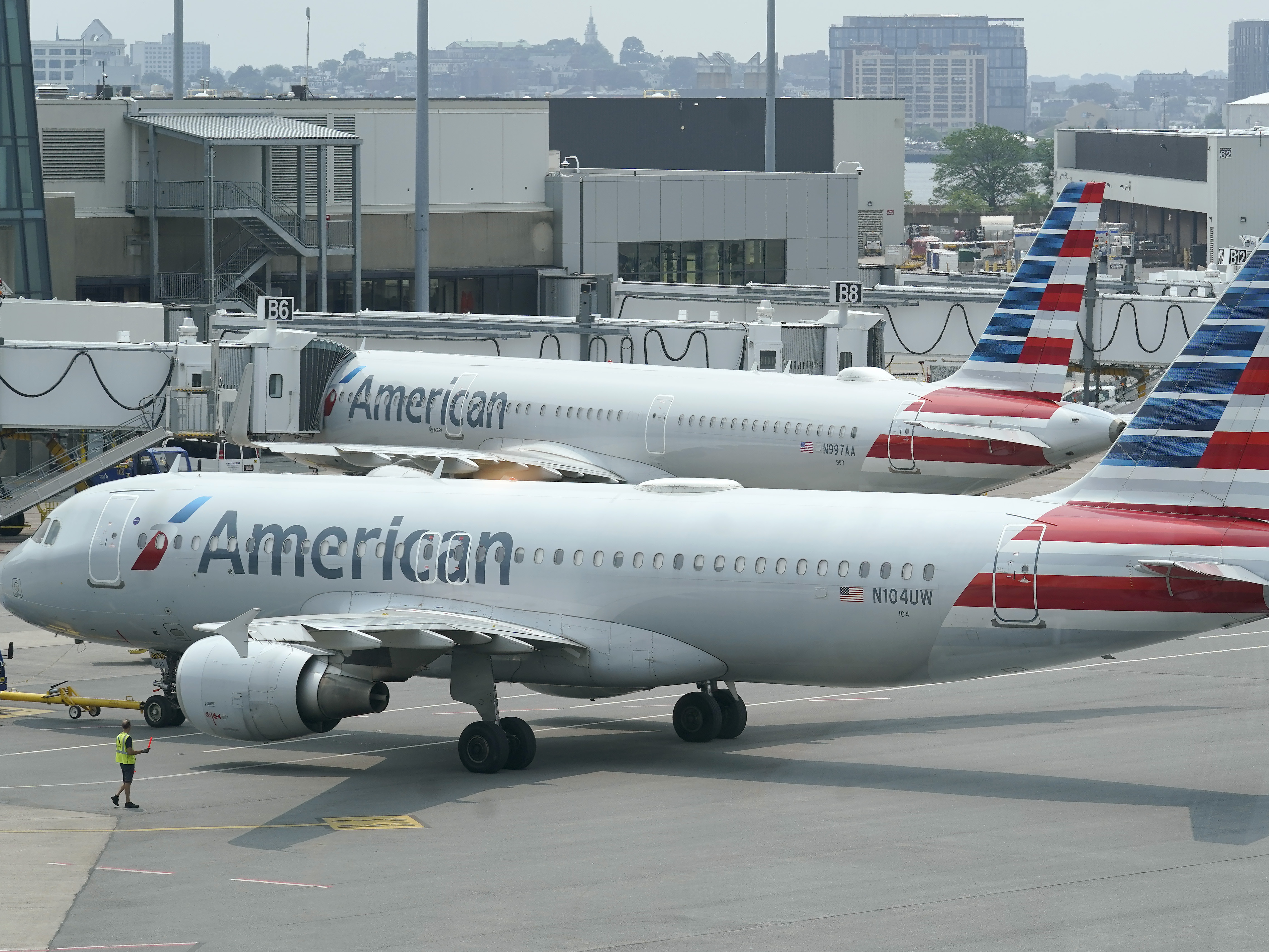 caption: American Airlines passenger jets prepare for departure near a terminal at Boston Logan International Airport, in Boston in July. More than 1,000 flights were cancelled this weekend due to weather and staffing shortages, the airline said.