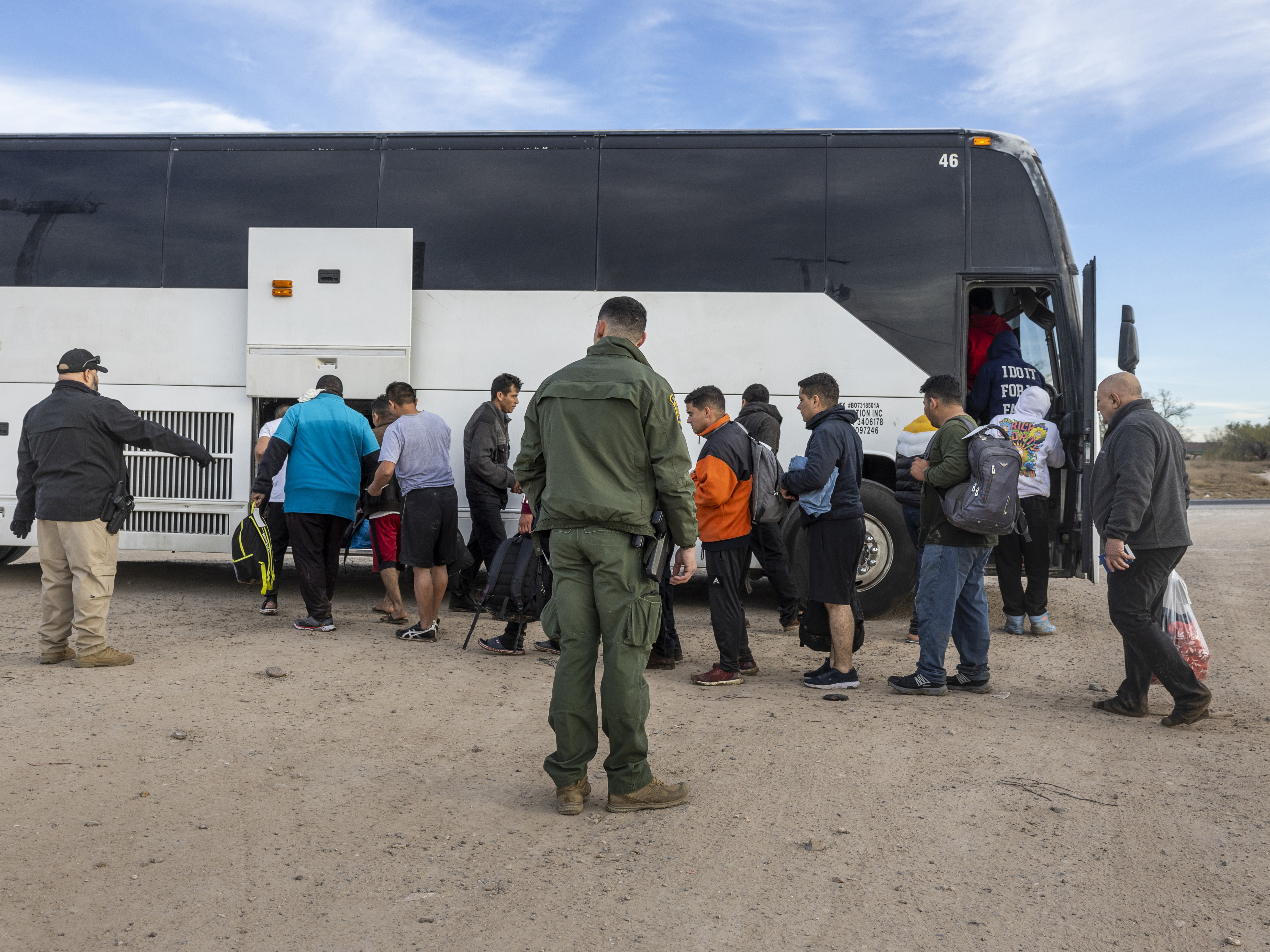 caption: Immigrants file into a U.S. Customs and Border Protection bus after crossing the U.S.-Mexico border on January 07, 2024 in Eagle Pass, Texas.