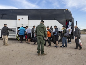 caption: Immigrants file into a U.S. Customs and Border Protection bus after crossing the U.S.-Mexico border on January 07, 2024 in Eagle Pass, Texas.
