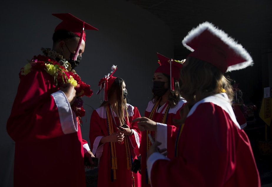 caption: Cleveland Stem High School seniors from left, Makana Haynes, Megan Louie, Isabella Caldejon and Aaliyah Caldejon talk before the start of the in-person commencement ceremony on Tuesday, June 15, 2021, at Memorial Stadium in Seattle.