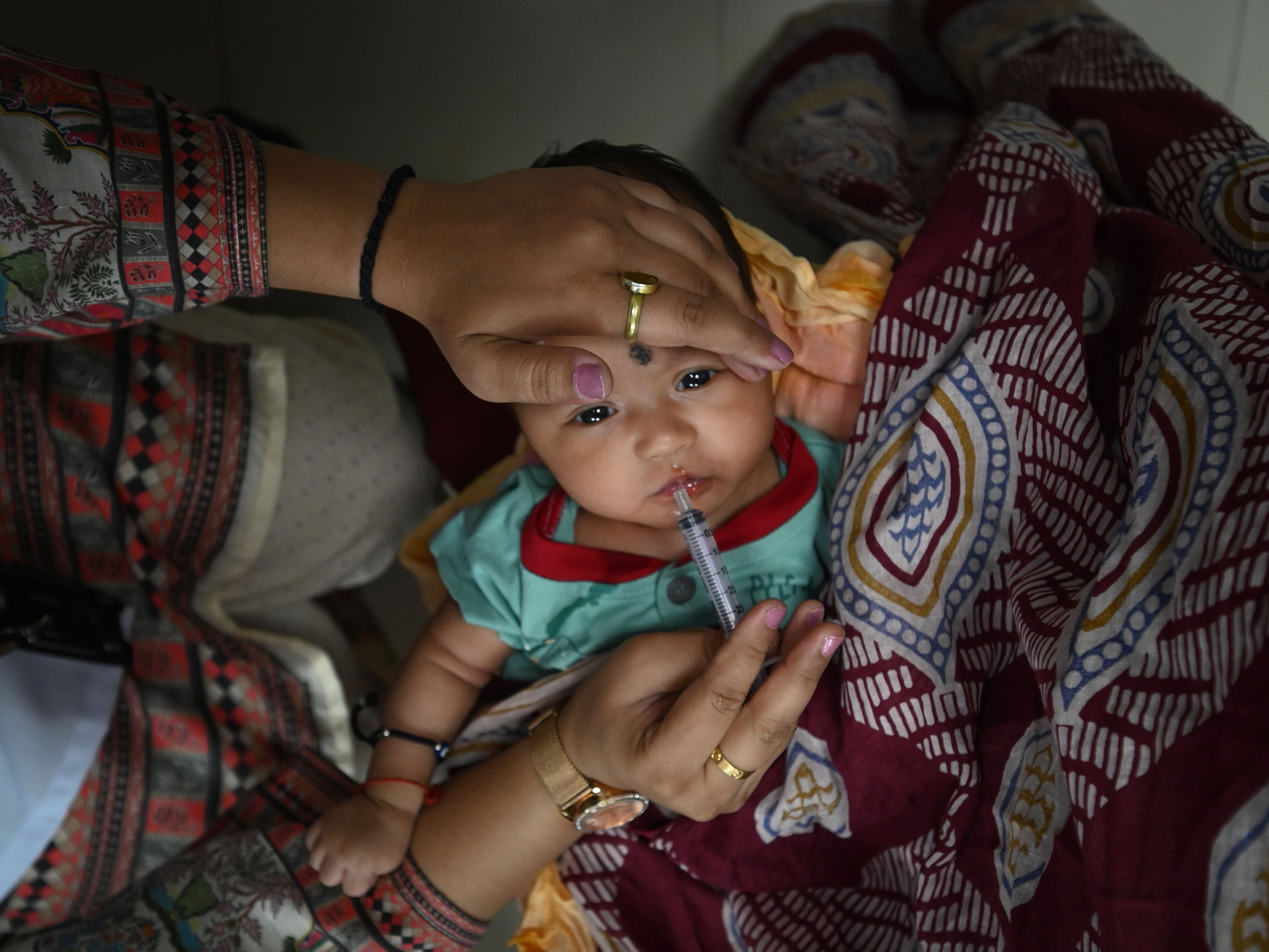 caption: A child gets an oral vaccine in New Delhi, India, on June 17. India has made notable progress in improving access to childhood vaccinations.