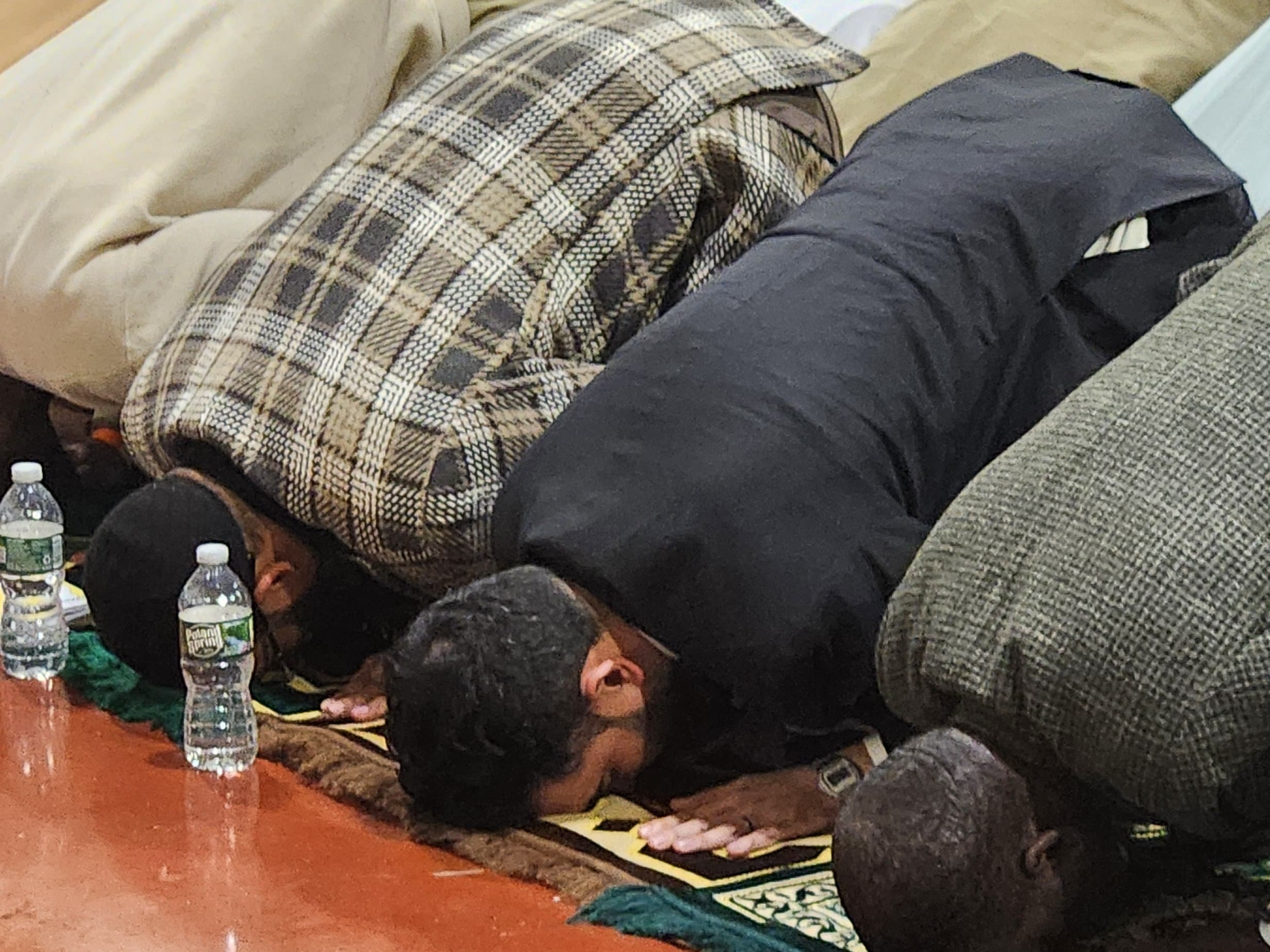 caption: New York City Mayor Zohran Mamdani, at center in a black suit, prayed and broke the daily Ramadan fast with men incarcerated at the city's Rikers Island jail complex.