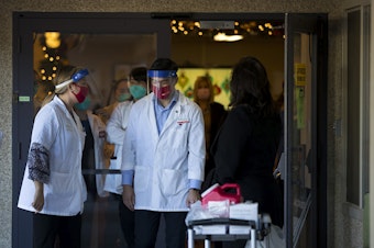 caption: Matthew Talavera, a pharmacist with CVS, pushes a cart of supplies ahead of administering the first doses of the Pfizer-BioNTech Covid-19 vaccine to staff members at the Life Care Center of Kirkland on Monday, December 28, 2020, in Kirkland. 
