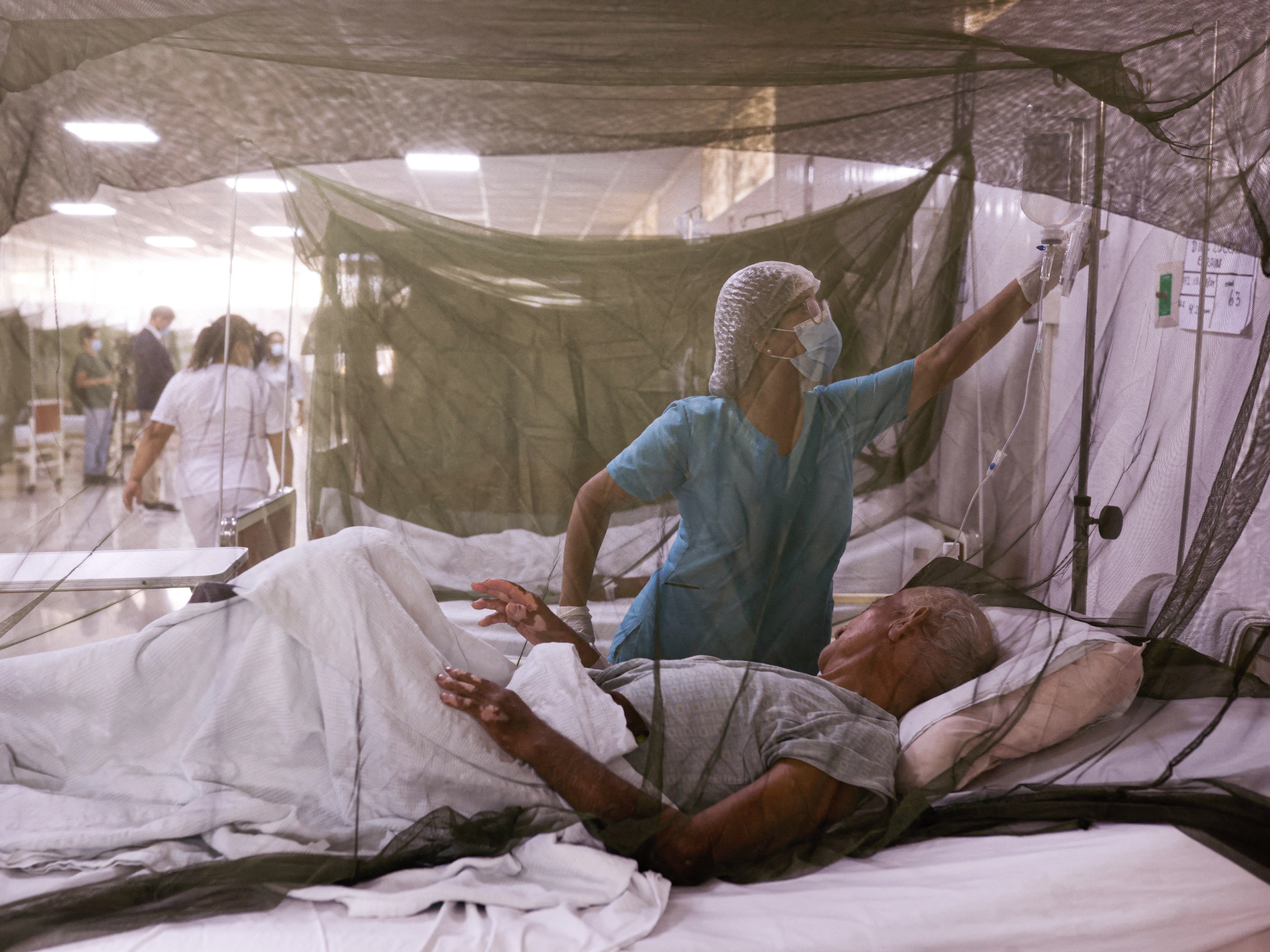 caption: A nurse takes care of a dengue fever patient at the Sergio Bernales National Hospital in the outskirts of Lima on April 17. The number of suspected cases in Peru so far this year is over 100,000.