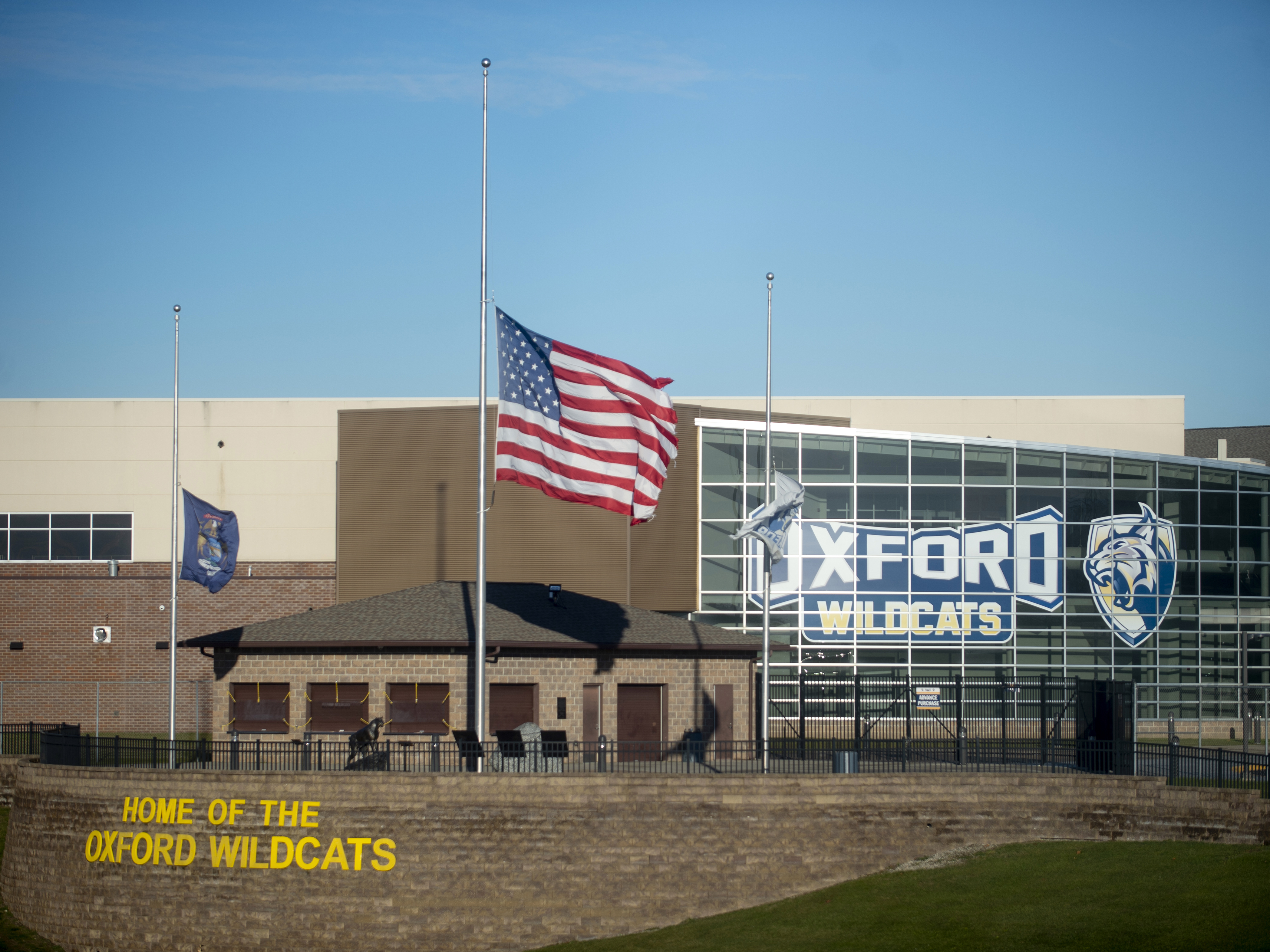 caption: The American flag flies at half-staff on Dec. 2, 2021, outside of Oxford High School in Oxford, Mich.