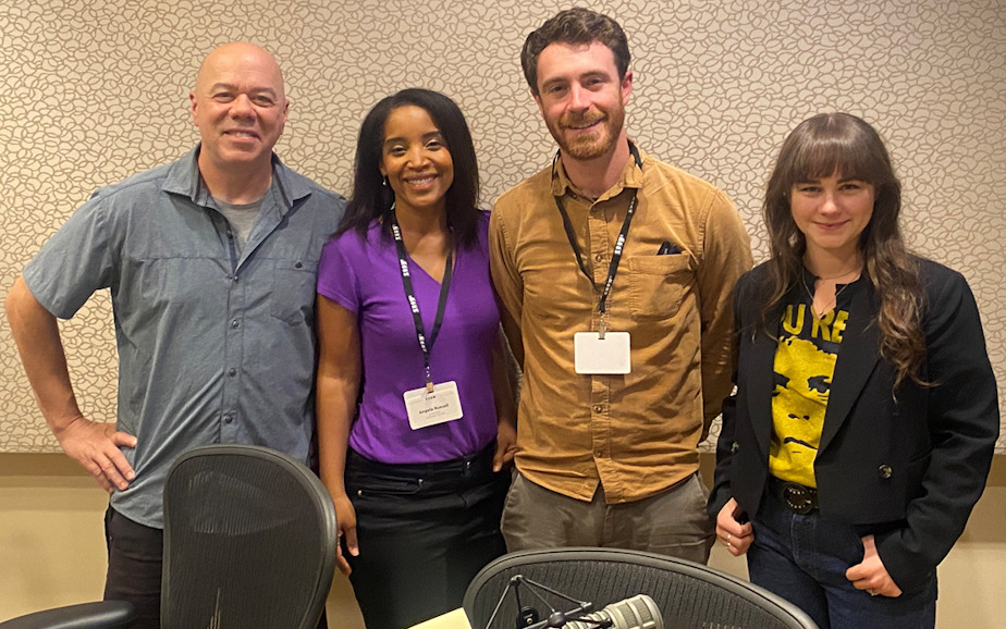 caption: Guest host Mike Lewis discusses the week’s news with Seattle Times David Kroman, host, writer, and producer Angela Poe Russell, and KUOW’s Monica Nickelsburg. 