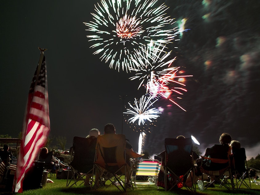 caption: Spectators watch as fireworks explode overhead during the Fourth of July celebration at Pioneer Park, on July 4, 2013, in Prescott, Ariz.