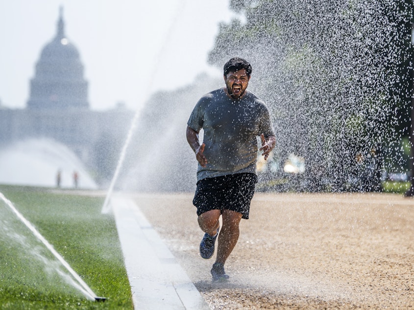 caption: If you must exercise when the the sun is high, dousing yourself with water, as this jogger did last month in steamy Washington, D.C., could help cool you down. Heat stroke is no joke, experts warn. Learn the signs to stay safe.