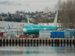 caption: Boeing is under heightened scrutiny from regulators and the public after a door plug panel blew off a jet in midair two months ago. Now the Justice Department is conducting a criminal investigation. Several Boeing 737 Max planes under construction in Renton, Wash. are shown outside the company's plant on February 27, 2024.