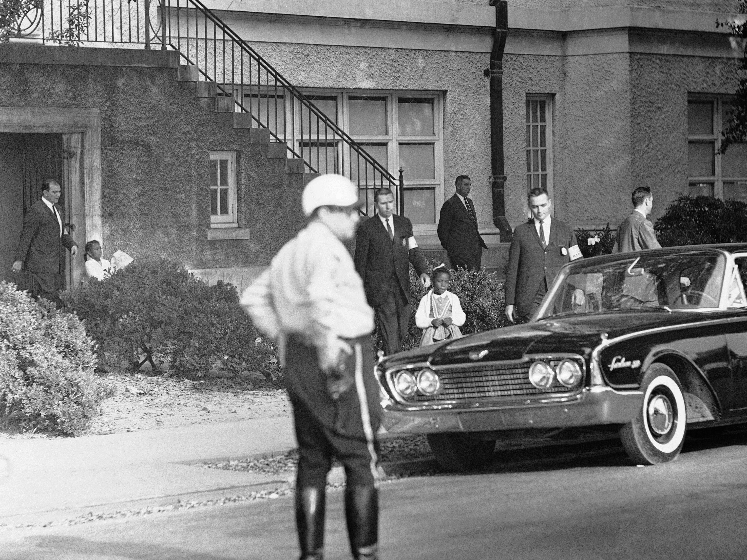 caption: Six-year-old Leona Tate is escorted by U.S. Marshals from McDonogh 19 Elementary School in New Orleans on Nov. 15, 1960. 