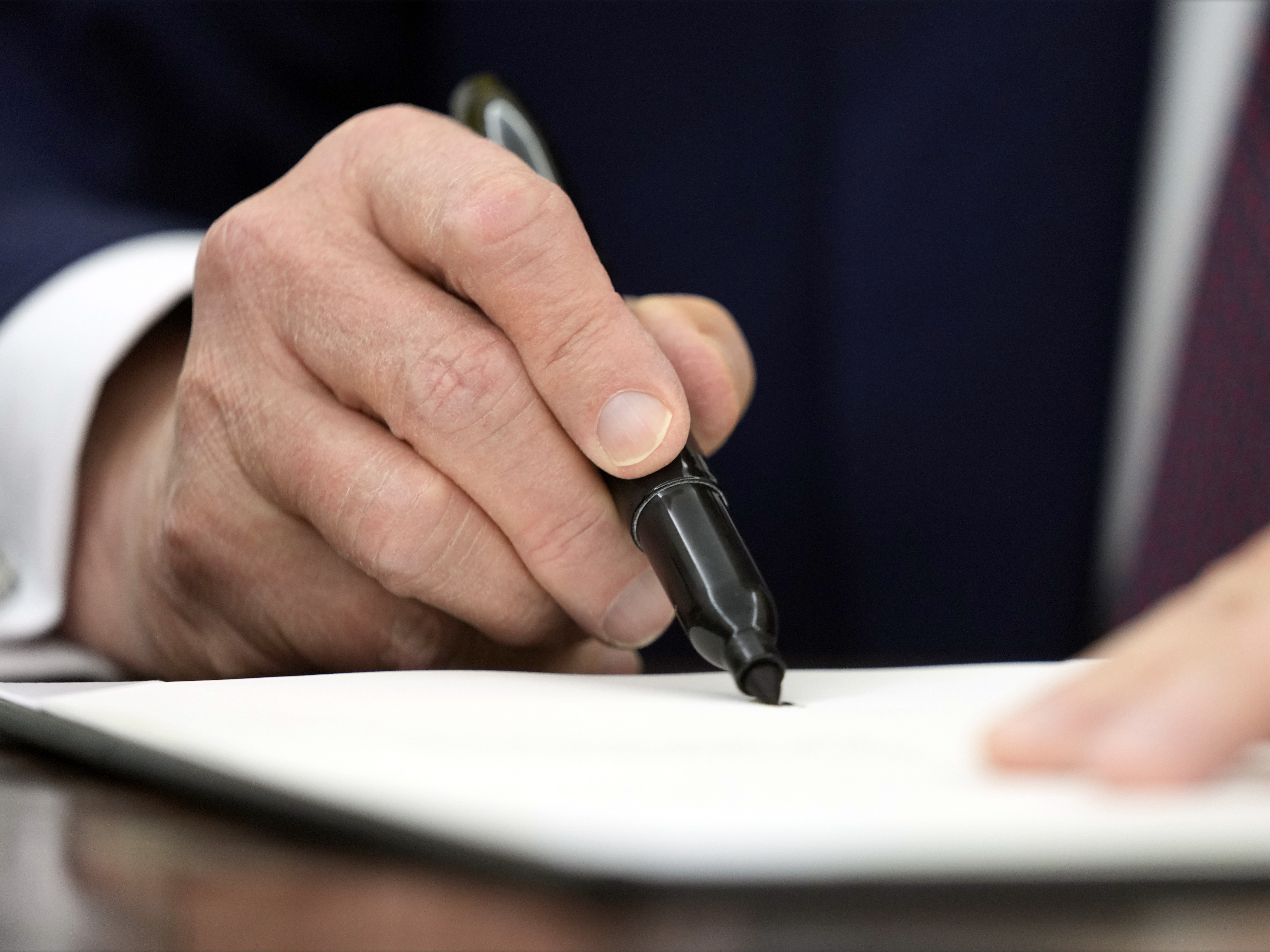 caption: President Donald Trump signs an executive order in the Oval Office of the White House, Jan. 23, 2025, in Washington.