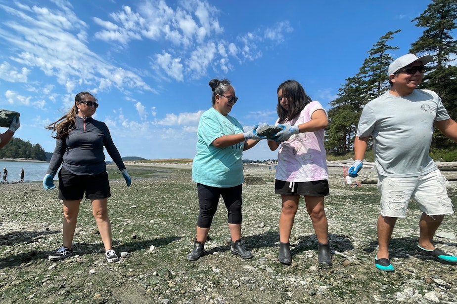 caption: Kiarra Williams of LaConner, Washington, passes a rock to her mother, Marcia Julius, at Kiket Island on Aug. 12.