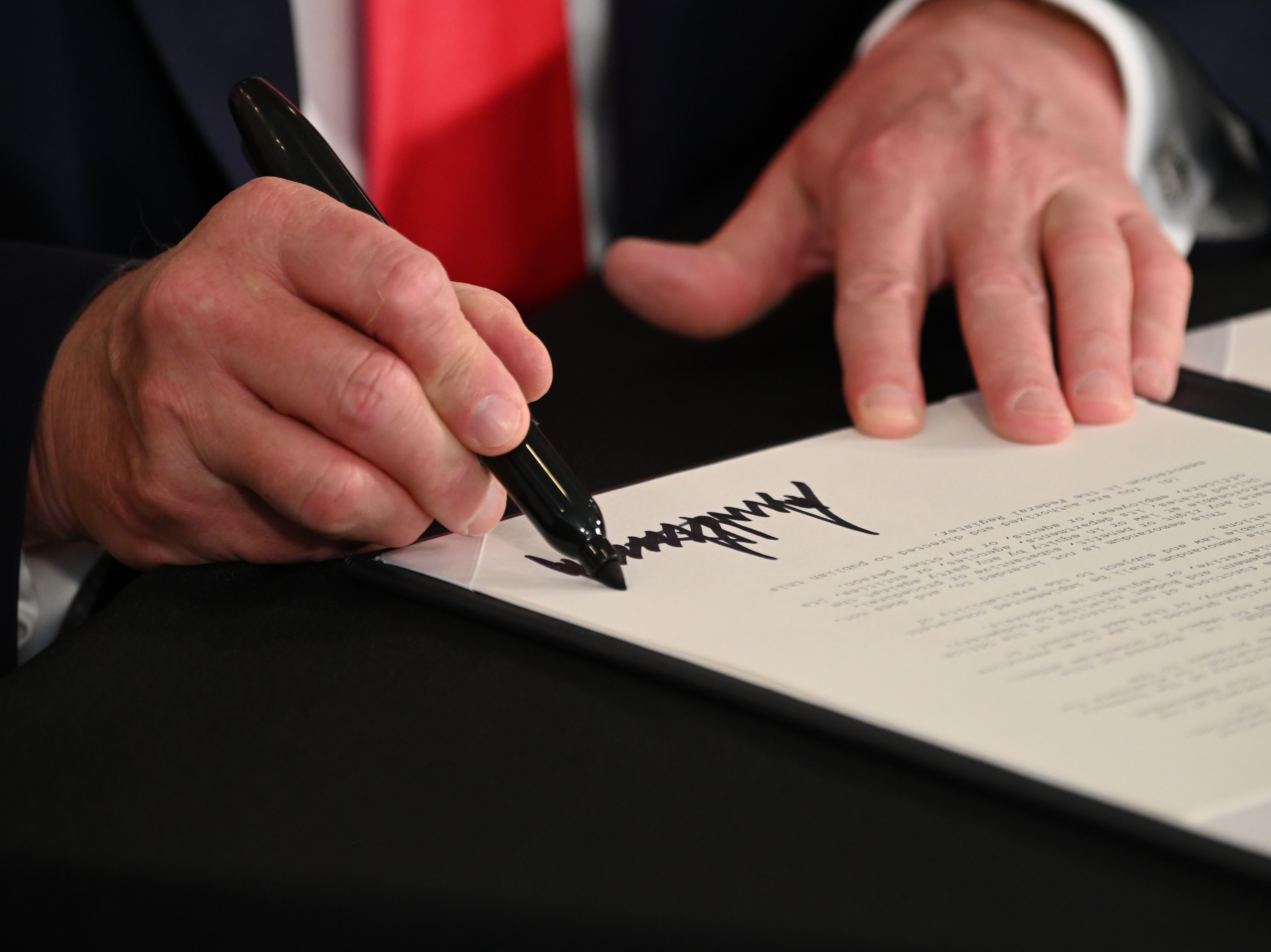 caption: President Trump signs executive actions regarding coronavirus economic relief during a news conference in Bedminster, N.J., on Saturday. A number of lawmakers are criticizing the measures' substance and constitutionality.