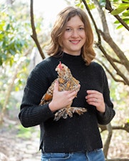 caption: Tove Danovich, journalist and author of "Under the Henfluence: Inside the World of Backyard Chickens and the People Who Love Them" poses for a photo with one of her pet chickens.
