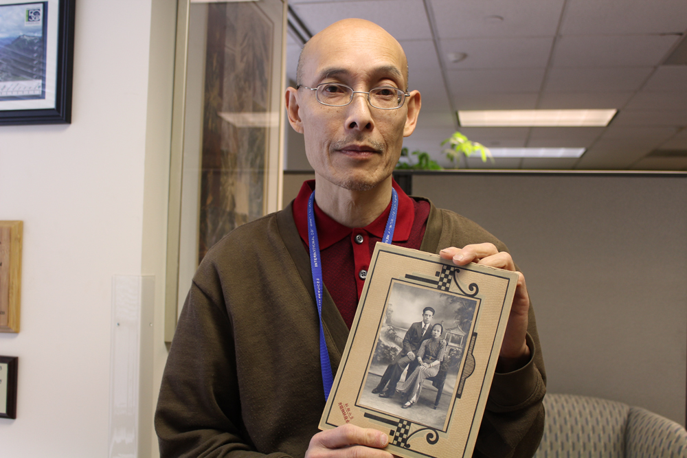 caption: Ron Chew works at the International Community Health Services. He holds a portrait of his parents. His grandfather came to the U.S. illegally during the Chinese Exclusion Act.