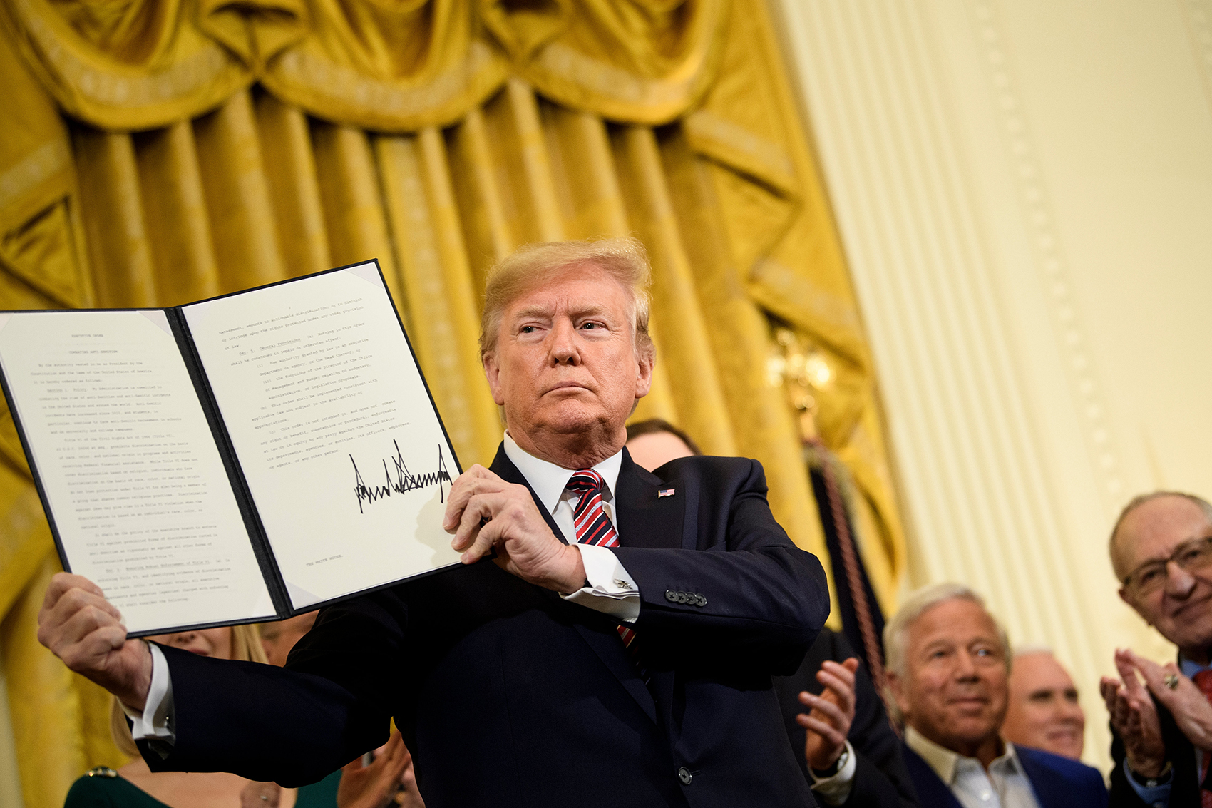 caption: President Trump shows an executive order regarding anti-Semitism during a Hanukkah reception in the East Room of the White House, Dec. 11, 2019. (Brendan Smialowski/AFP via Getty Images)