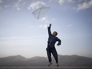 caption: In this photo made by Associated Press photographer Anja Niedringhaus, an Afghan boy flies his kite on a hill overlooking Kabul, Afghanistan, May 13, 2013.