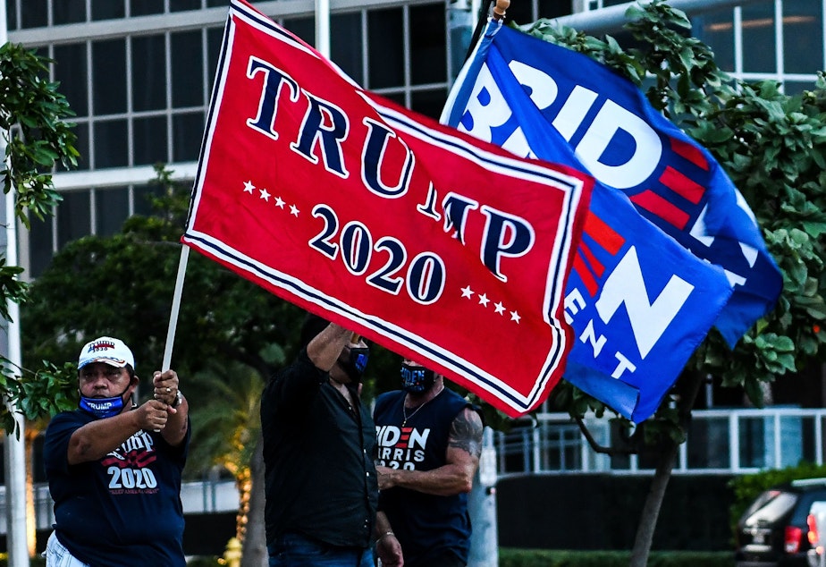 caption: Supporters of President Trump and Democratic presidential nominee Joe Biden wave flags prior to Biden's arrival for a townhall in Miami, Florida.