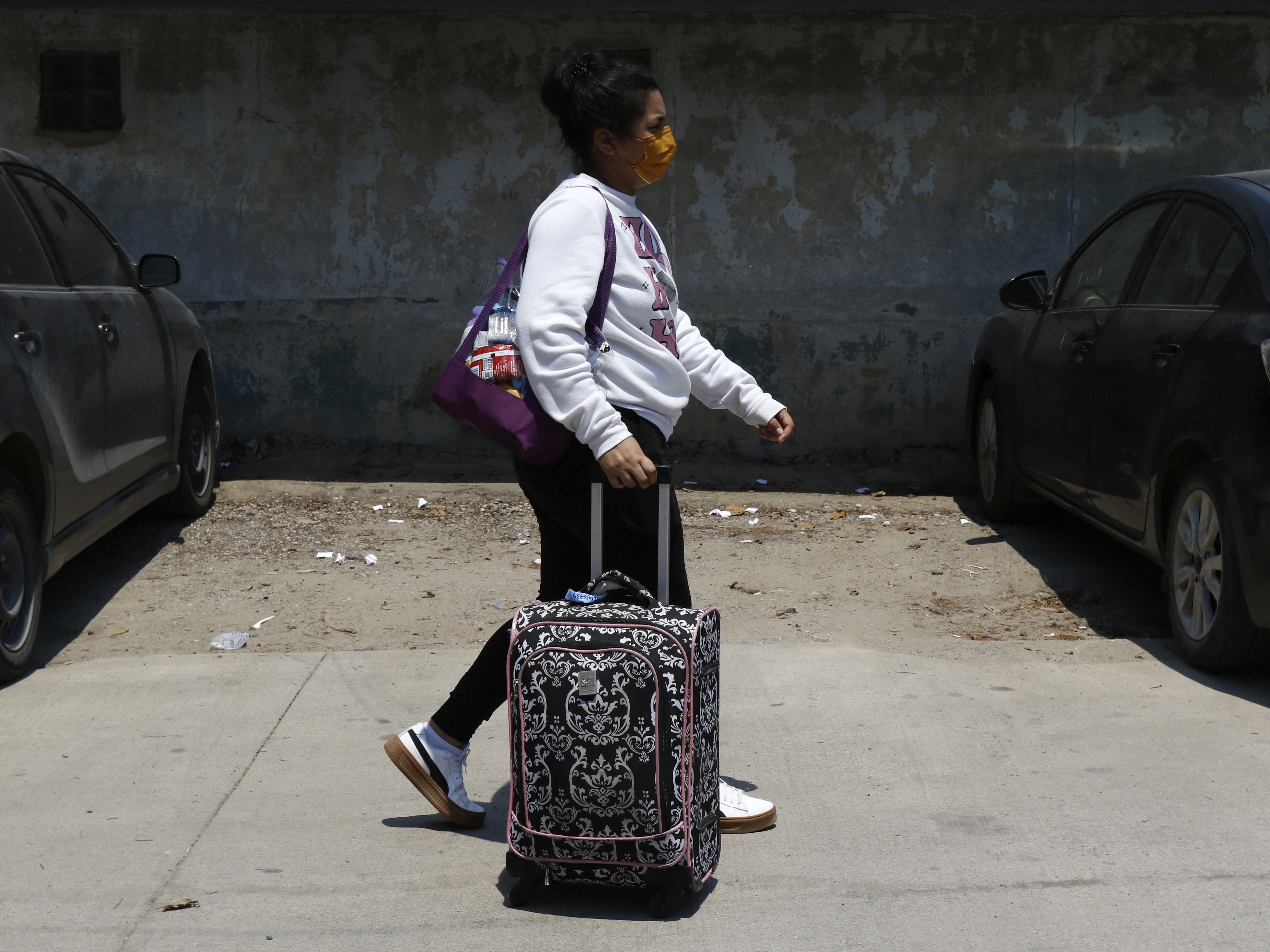 caption: A Honduran migrant who returned voluntarily from the United States walks after arriving at Ramon Villeda Morales Airport in San Pedro Sula, Honduras on Monday.