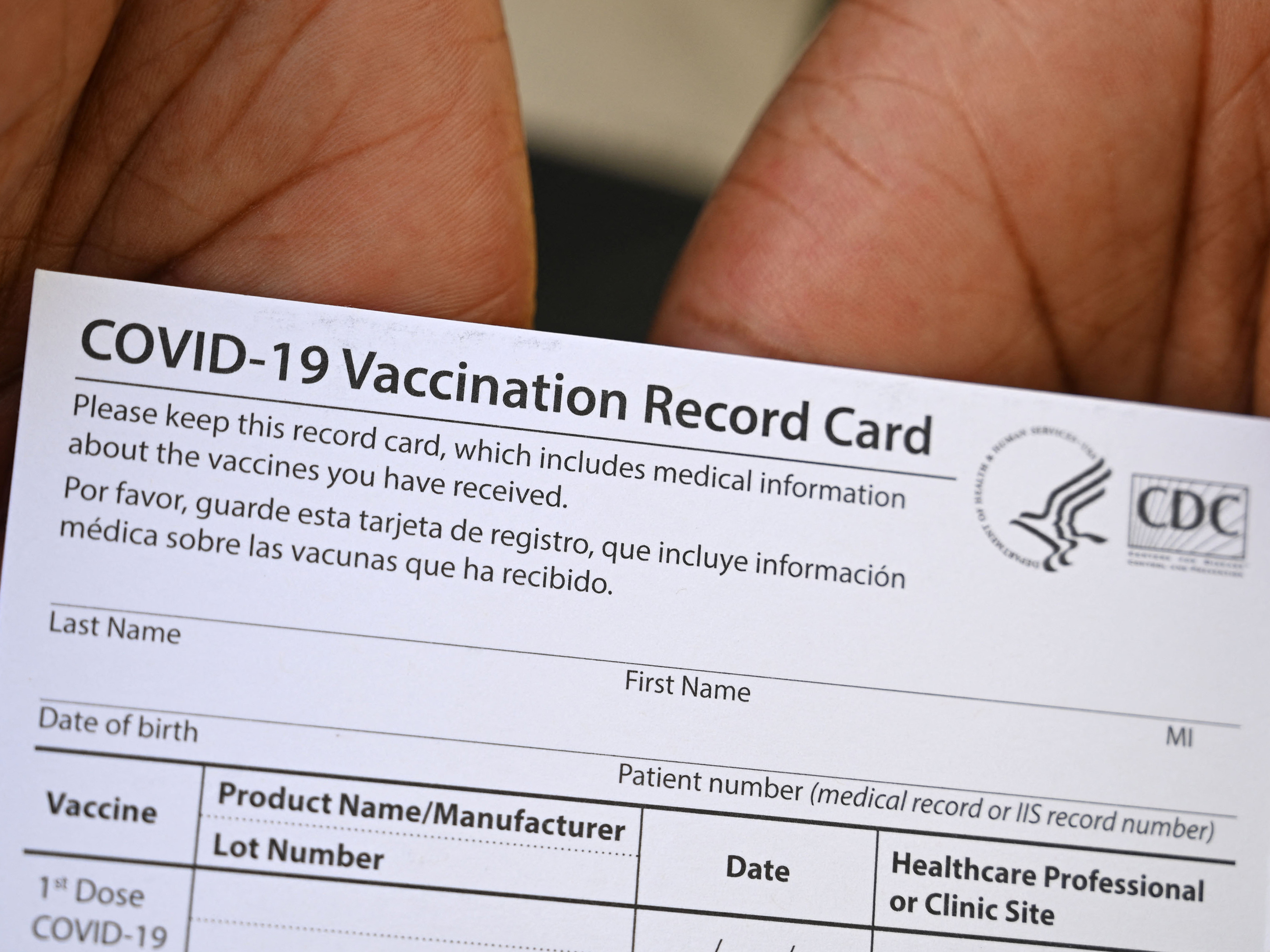 caption: A healthcare worker displays a Covid-19 Vaccination Record Card at a health center in Los Angeles earlier this month.