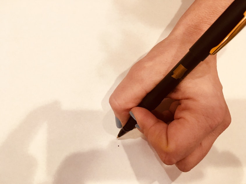 caption: Kristin Rowe-Finkbeiner displays a pen from the signing ceremony of Washington State's Equal Pay Opportunity Act.