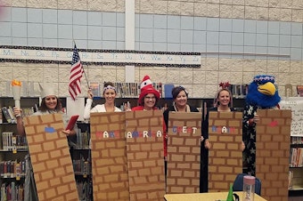 caption: In another photo put on social media by the Middleton School District, educators can be seen posing with segments of a wall emblazoned with "Make America Great Again." CREDIT:  Middleton Heights School District via Facebook