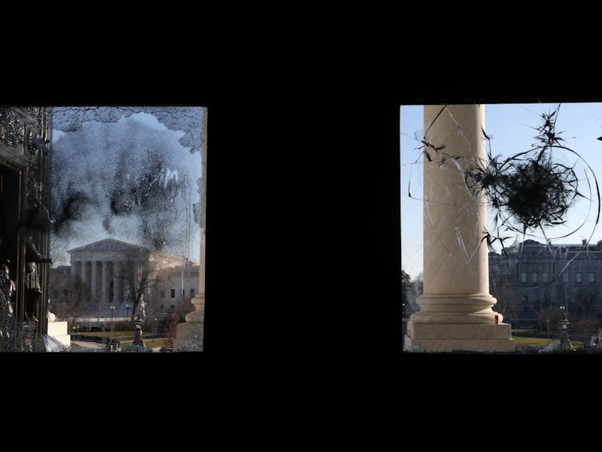 caption: The U.S. Supreme Court is seen through a broken window at an entrance of the U.S. Capitol Wednesday.