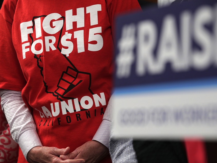 caption: An activist wears a "Fight For $15 and a Union" t-shirt at the U.S. Capitol in 2019 as lawmakers took on legislation to raise the federal minimum wage.