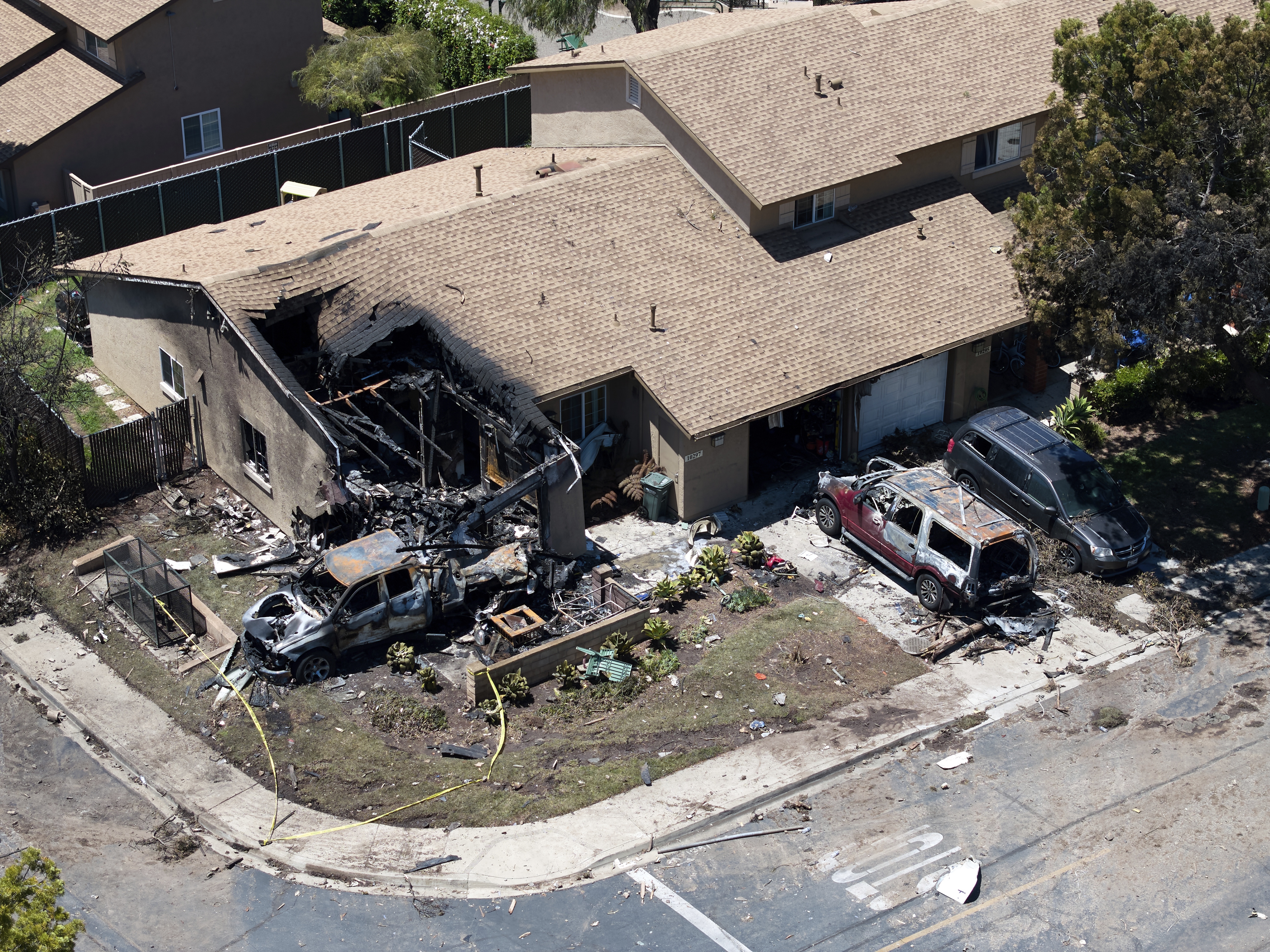 caption: Debris covers the ground after a small plane crashed into a San Diego neighborhood, setting homes and cars on fire and forcing evacuations early Thursday, May 22, 2025.