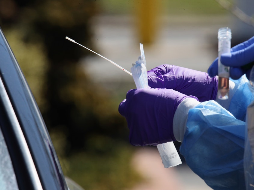 caption: Medical workers prepare to use a swab to administer a coronavirus test at a drive-through center on March 21 in Jericho, N.Y.