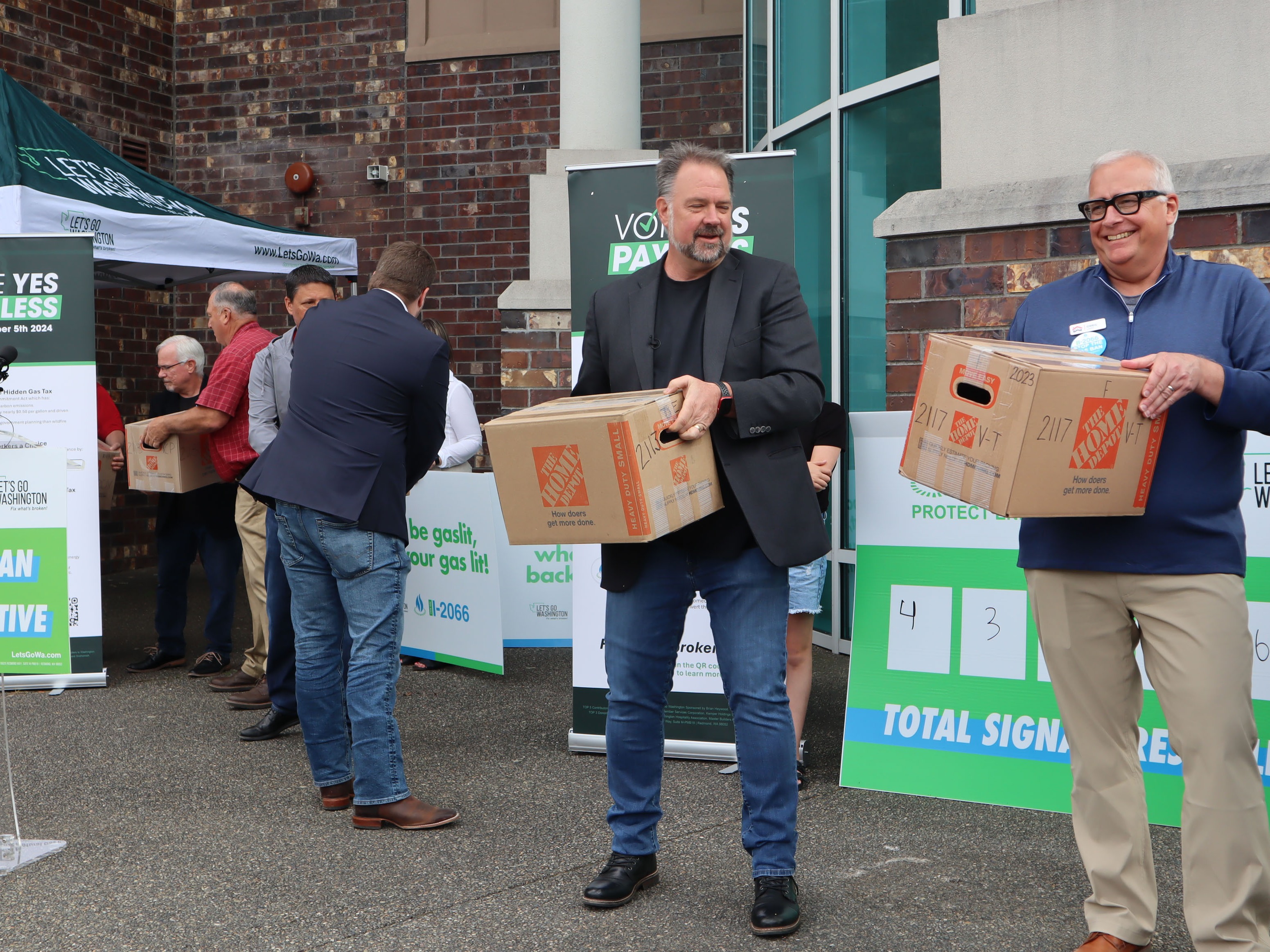 caption: Let's Go Washington founder Brian Heywood (center) helps turn in boxes of signatures supporting I-2066, the initiative focused on protecting natural gas access, at the Secretary of State's Tumwater office Tuesday, July 2, 2024.