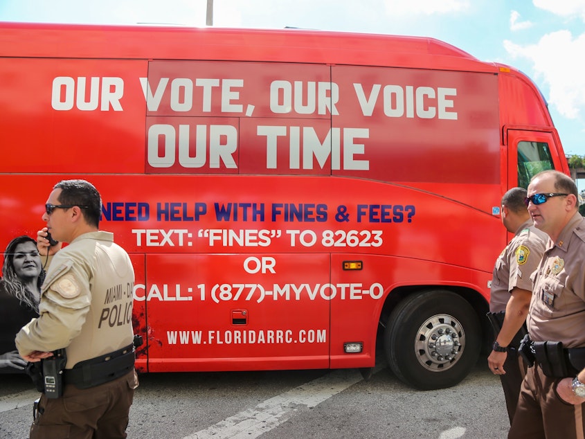 caption: A tour bus, sponsored by the Florida Rights Restoration Coalition, pulls up to a Miami-Dade County courthouse ahead of a hearing aimed at restoring the right to vote under Florida's Amendment 4 on Nov. 8, 2019.